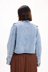 Chaqueta de jean estilo napoleónico color negro, con cuello mao, hombreras y filas dobles de botones metálicos grabados.