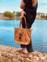 Bolso tote de cuero color marrón con doble asa de hombro y bolsillo externo con cierre.