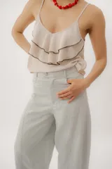Musculosa negra con escote en V, breteles finos regulables y doble volado frontal con pespuntes.
