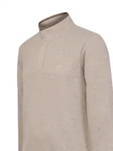 Sweater de tejido de punto color beige, con cuello alto y cierre frontal parcial con botones ocultos. Presenta un diseño de textura acanalada y un pequeño logo bordado en el pecho.