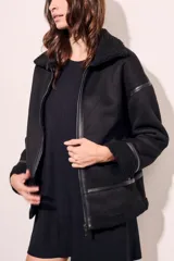 Campera tipo gamulán de corte oversize, color negro, con interior y cuello de corderito sintético. Presenta cierre frontal, detalles de costuras y puños con terminación en corderito.