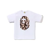 Camiseta blanca de manga corta con un gran estampado frontal de la cabeza de mono (Ape Head) con patrón de camuflaje en tonos marrones y beige.