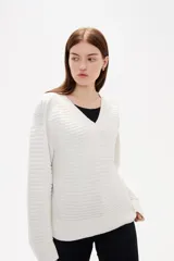 Sweater de punto color blanco, con cuello en V, manga larga y diseño holgado.