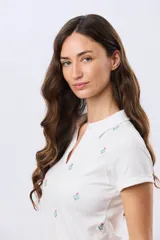 Remera polo de algodón color beige con mangas cortas, escote en V y cuello camisero. Presenta delicados mini bordados florales distribuidos en toda la prenda.
