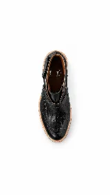 Botineta de cuero negro con textura efecto cocodrilo, taco cuadrado de madera en tono claro, plataforma sutil y tira decorativa con argolla metálica en el lateral.