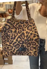 Bolso tote de cuero con estampado animal print en tonos beige y marrón.
