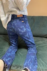 Pantalón de jean de corte recto con estampado de hojas en tonos azules.