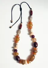 Collar de diseño ajustable con cuentas de resina, acrílico y plástico en tonos tierra, marrones y dorados, con cierre de cordón negro.