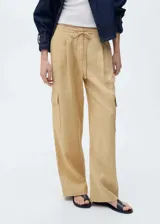 Pantalon cargo de lino color beige, con tiro medio, cintura elástica con lazo ajustable, bolsillos de parche con solapa en los laterales y corte recto.