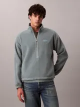 Buzo polar de Calvin Klein con cuello alto y cierre de media cremallera frontal. Presenta un diseño de manga larga con puños elásticos y un parche con el logo de la marca en el pecho.