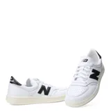 Championes urbanos New Balance modelo Court, color blanco con logo lateral y detalle en talón en color negro. Presentan puntera perforada para mayor ventilación y suela de goma en tono crema.
