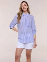 Camisa de corte clásico y silueta relajada con diseño de rayas verticales en azul y blanco, cuello camisero tradicional, cierre frontal con botones y bolsillo aplicado en el pecho con rayas horizontales. Cuenta con mangas largas con presillas para arremangar y ruedo redondeado.
