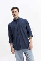 Camisa de manga larga color azul marino con textura, cuenta con cuello clásico, cierre frontal con botones y un bolsillo en el pecho.