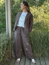 Blazer azul marino con rayas verticales blancas, confeccionado en lino italiano. Tiene botones de coco, solapas clásicas y bolsillos delanteros.