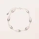 Pulsera plateada con eslabones finos y dijes ovalados con incrustaciones de circonias. Cuenta con cierre de mosquetón y cadena de extensión.