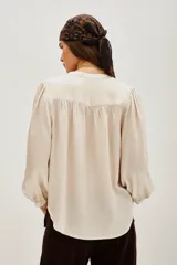 Camisa color crema de manga larga con cuello mao, botones a tono y frunces en mangas, espalda y hombros.