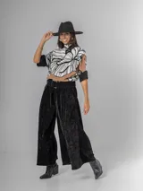 Pantalón tipo palazzo de corte oversized, confeccionado en tela con textura aterciopelada en color negro. Presenta cintura alta con pinzas, bolsillos laterales y un cinturón ancho integrado con hebilla al tono.