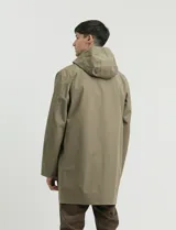 Gabardina con capucha de corte recto y largo medio. Cuenta con cierre frontal engomado, cartera con botones a presión, bolsillos laterales y tejido repelente al agua y al viento.