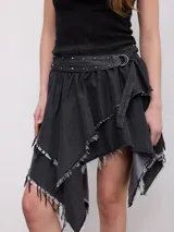 Minifalda asimétrica de denim color gris oscuro, con diseño desmechado en los bordes. Incluye un cinturón incorporado con tachas metálicas y hebilla de argolla redonda.