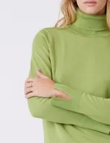 Polera de tejido fino, color rosado, con cuello alto, manga larga y detalle de tajo en los puños.