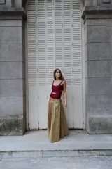 Pollera larga de corte amplio, color verde oliva con detalles de costuras verticales en tono bordó. Presenta una cintura alta y una caída fluida.