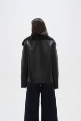 Chaqueta de eco-cuero negro con interior y cuello de piel sintética, diseño holgado, manga larga y cierre frontal con un botón.
