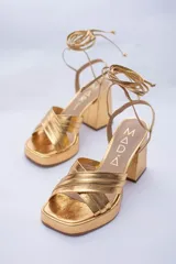 Sandalias color beige con plataforma y tacón cuadrado. Presentan tiras cruzadas en el empeine y tiras largas para atar alrededor del tobillo.