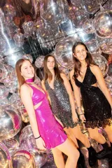 Vestido corto negro con estampado de plumas doradas, escote en V, breteles finos cruzados en la espalda, cut-outs laterales y volado en el ruedo.