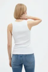 Musculosa blanca de algodón al cuerpo, con cuello redondo a la base y delicado bordado frontal de flor con cuentas.