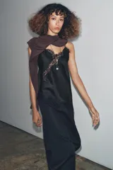 Top lencero negro de escote pico y tirantes finos. Presenta aplicación de encaje a tono en el escote y el bajo asimétrico.