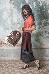 Mochila de cuero color blanco y marrón óxido con detalles metálicos color cobre. Tiene dos bolsillos frontales con cierre y correas ajustables. Diseño moderno y vibrante con personalidad única.