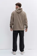 Buzo con capucha tipo canguro confeccionado en tela de corduroy color marrón. Presenta cordones blancos en contraste, bolsillo frontal tipo canguro y logo bordado sutil en el pecho.