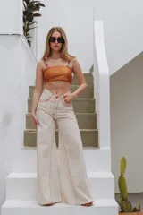 Jean wide leg color crudo, de tiro alto y corte amplio con botamanga deshilachada. Cuenta con costuras en hilo rojo en contraste y detalles de bordados bajo los bolsillos delanteros.
