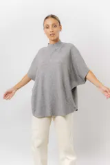 Sweater de tejido de punto color negro, con cuello semi alto y mangas cortas amplias. Presenta una silueta relajada y caída fluida.