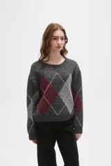Sweater de punto con diseño de rombos argyle en tonos gris, bordó y gris claro. Presenta cuello redondo, mangas largas y un corte holgado.