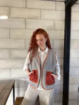 Chaleco gris de paño con bolsillos delanteros de tejido rústico color ladrillo y ribete color ocre. Diseño holgado.