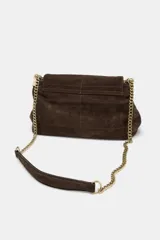 Bolso de hombro confeccionado en piel de gamuza color marrón, con diseño estructurado y pespuntes decorativos en la solapa. Cuenta con una correa de cadena metálica dorada con refuerzo de piel y cierre imantado.