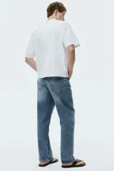 Jean de corte holgado estilo loose, confeccionado en denim de algodón grueso en tono azul claro con lavado desgastado. Presenta diseño de cinco bolsillos, tiro bajo y pierna ancha y redondeada.