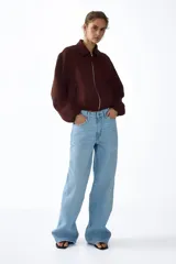 Campera oversized de sarga color marrón, con cuello, cierre frontal y bolsillos laterales ribeteados. Cuenta con mangas abullonadas, puños elásticos y bajo globo para una silueta redondeada.