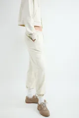 Pantalón jogger color beige, confeccionado en mezcla de algodón y poliéster, con cintura elástica ajustable mediante cordón y puños elásticos en los tobillos.