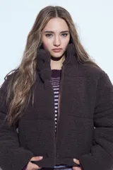 Campera puffer de corderito negro con cuello alto y diseño oversized. Presenta una textura tipo teddy, cierre frontal y corte a la cintura.
