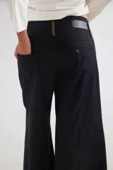 Pantalón de tiro medio-alto con piernas anchas y corte recto. Presenta cierre frontal con botón, bolsillos laterales y detalles de costuras verticales. Confeccionado en tencel.