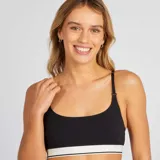 Top de lactancia negro con tirantes ajustables y broches para facilitar la alimentación. Presenta una banda elástica blanca con una línea negra en el borde inferior.