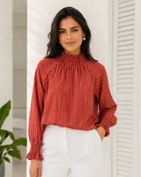 Blusa de seda color rojo terracota con diseño de rayas verticales blancas, cuello smock fruncido y mangas largas amplias con puños elásticos fruncidos.