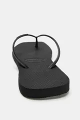 Sandalias planas de dedo tipo ojota, color negro, con diseño minimalista y suela de goma con textura en relieve.