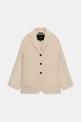 Abrigo corto de lana con cuello solapa, manga larga y cierre frontal con botones. Presenta bolsillos de plastrón en el delantero.