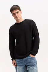 Sweater de cuello redondo negro con tejido texturizado, de manga larga y diseño liviano con caída natural.