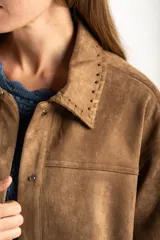 Sobrecamisa de gamuza sintética color camel, con corte oversize, cuello clásico con detalle de costura, cierre frontal con botones metálicos y mangas largas.
