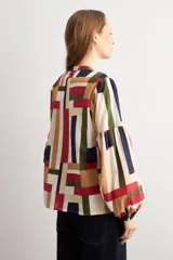 Camisa de manga larga con estampado geométrico multicolor en tonos beige, rojo, azul marino y verde, cuello mao y cierre frontal con botones.