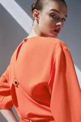Vestido midi color naranja de la colección ZW de Zara, con cuello redondo, manga corta y detalle de tejido drapeado con volados en el delantero. Cuenta con cierre en la espalda con abertura y botón.